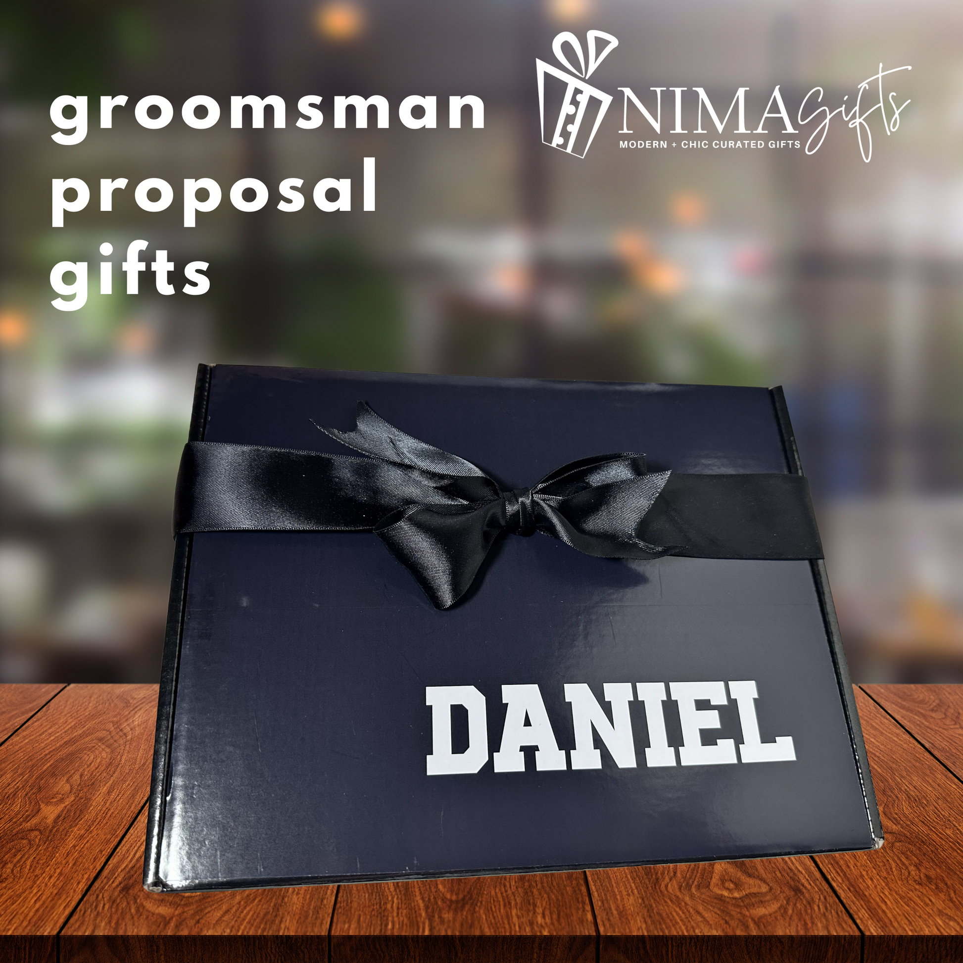 Black gift box with a black ribbon and 'DANIEL' text on a wooden surface, with NIMA Gifts branding.