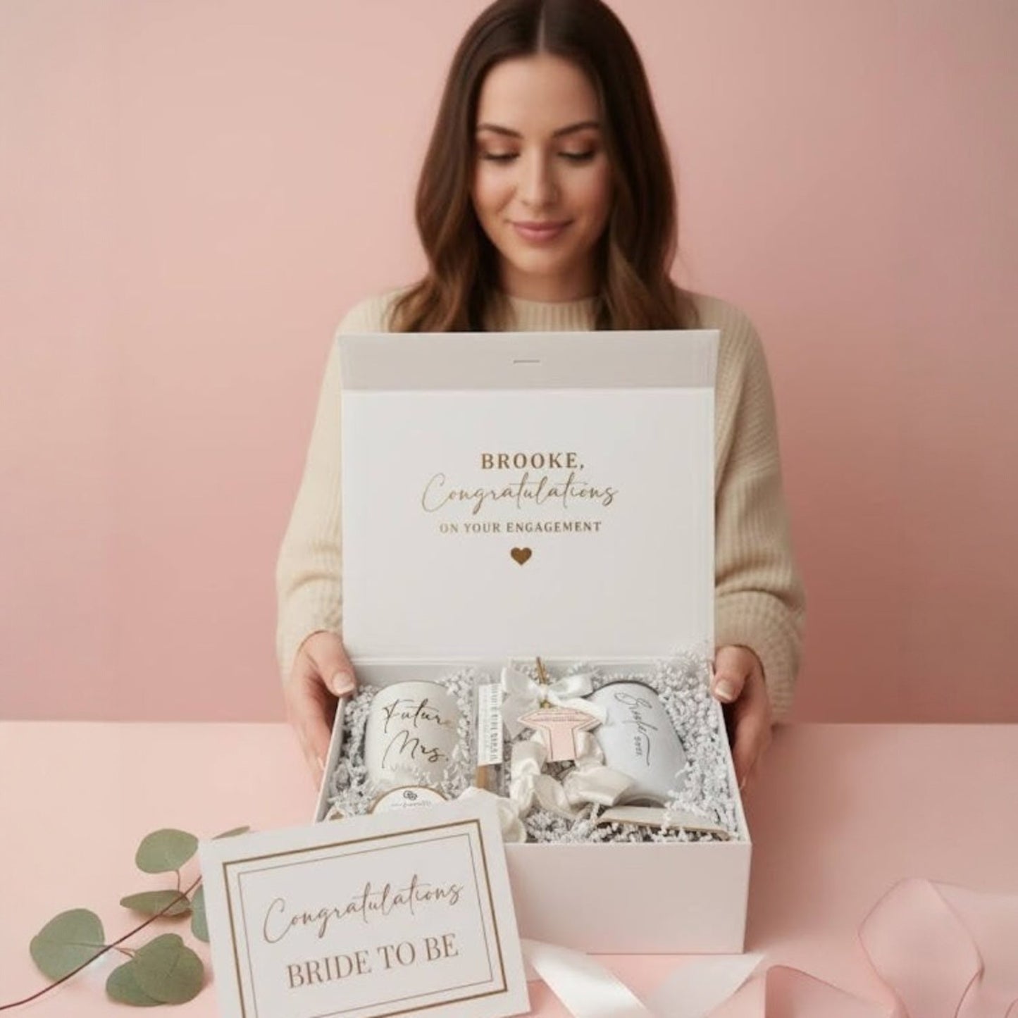 Woman holding a gift box with 'Congratulations on your engagement' and 'Congratulations Bride to Be' text on a pink background.