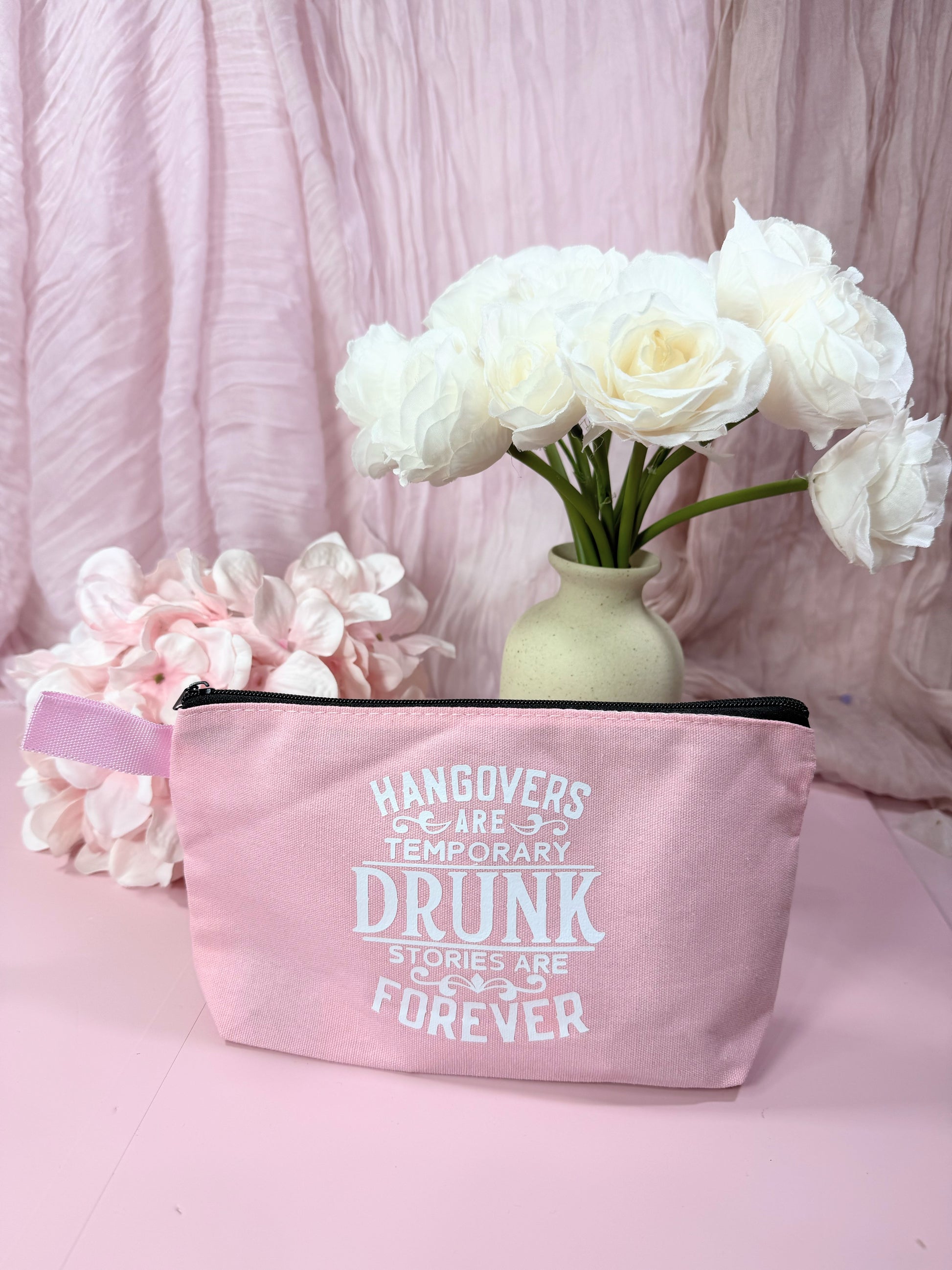 Pink pouch with humorous text on a pink background with flowers