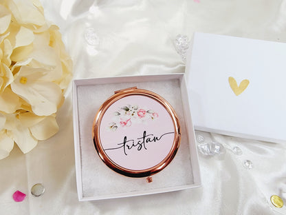 Compact mirror with floral design and 'tristan' text in a box on a soft fabric background