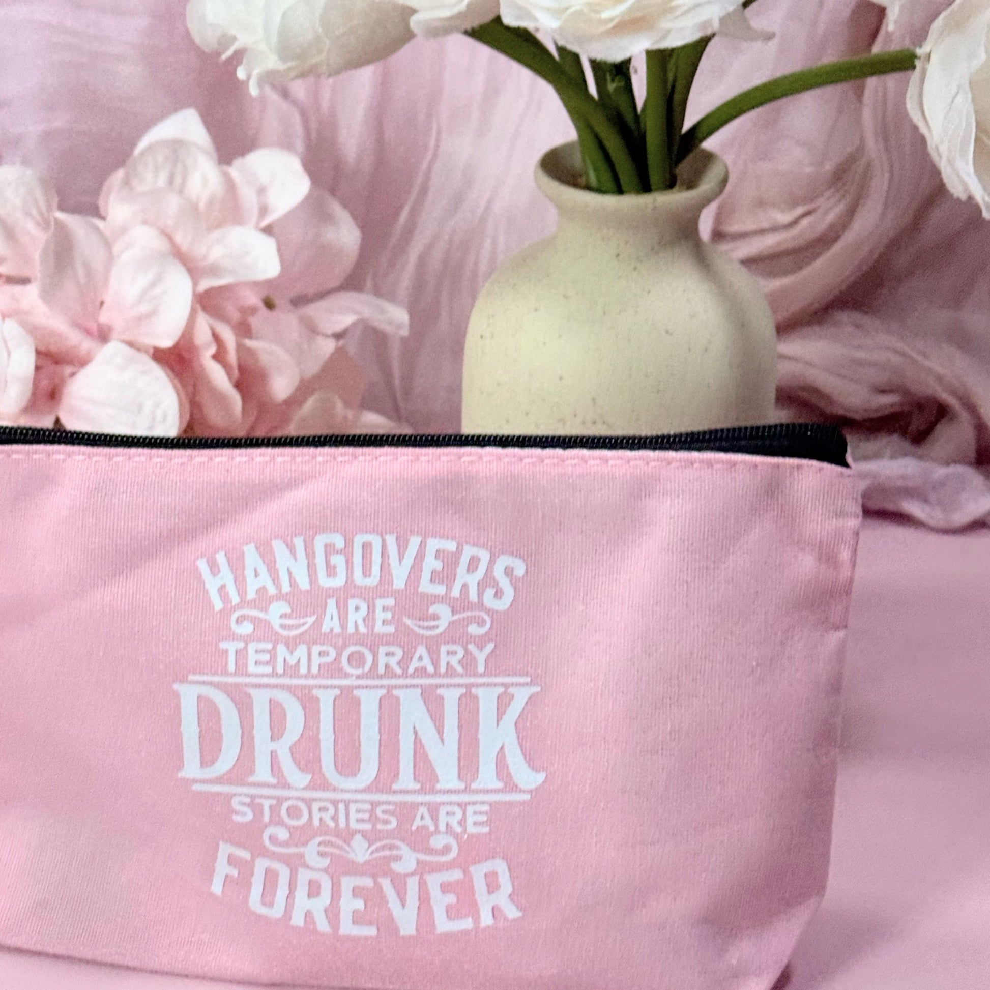 Pink bag with humorous text and a vase of white flowers on a pink background