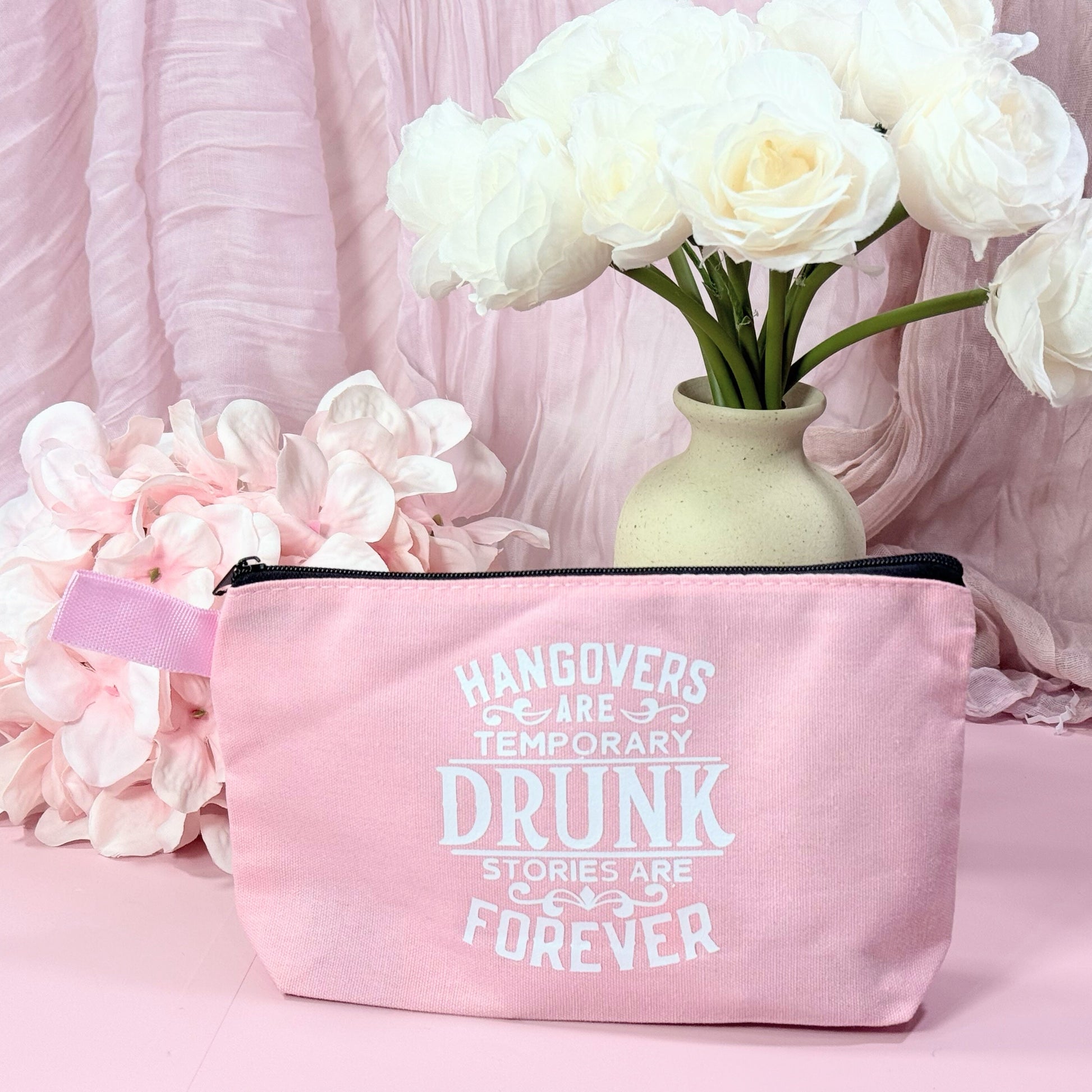Pink pouch with humorous text on a pink background with flowers