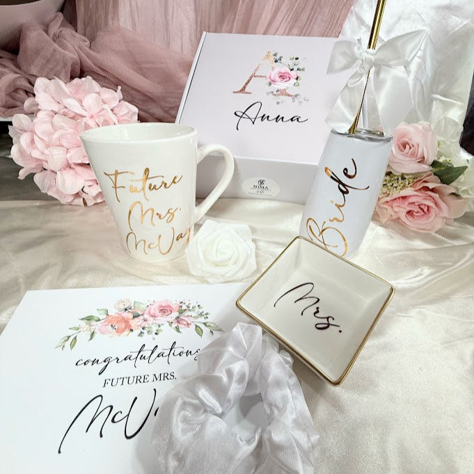 Bridal shower gift set with 'Future Mrs.' mug, 'Bride' tumbler, and decorative items on a table.