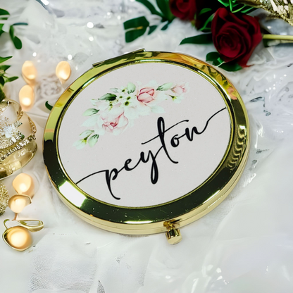 Round compact mirror with floral design and 'peytou' text on a decorative background with candles and flowers.