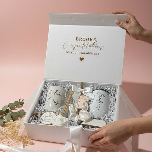 Engagement gift box with decorative items on a pink background