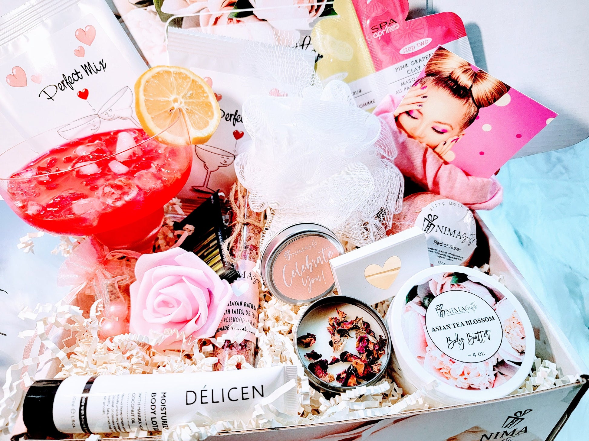 This birthday gift box includes a peonies gift box filled with various bath and body products, including a pink bath bomb, a white bath pouf, a pink rose, a candle, a bottle of body lotion, and a jar of body butter. The box is filled with shredded paper and has a white ribbon tied around it. The products are arranged in a visually appealing way and are ready to be gifted.