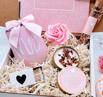 Personalized pink wine tumbler with metal straw and pink satin bow, pink foam rose, glass vial of bath salts, 4oz lavender candle in gold tin, gold heart matchbox, all arranged in custom-designed gift box with matching Happy Birthday card.