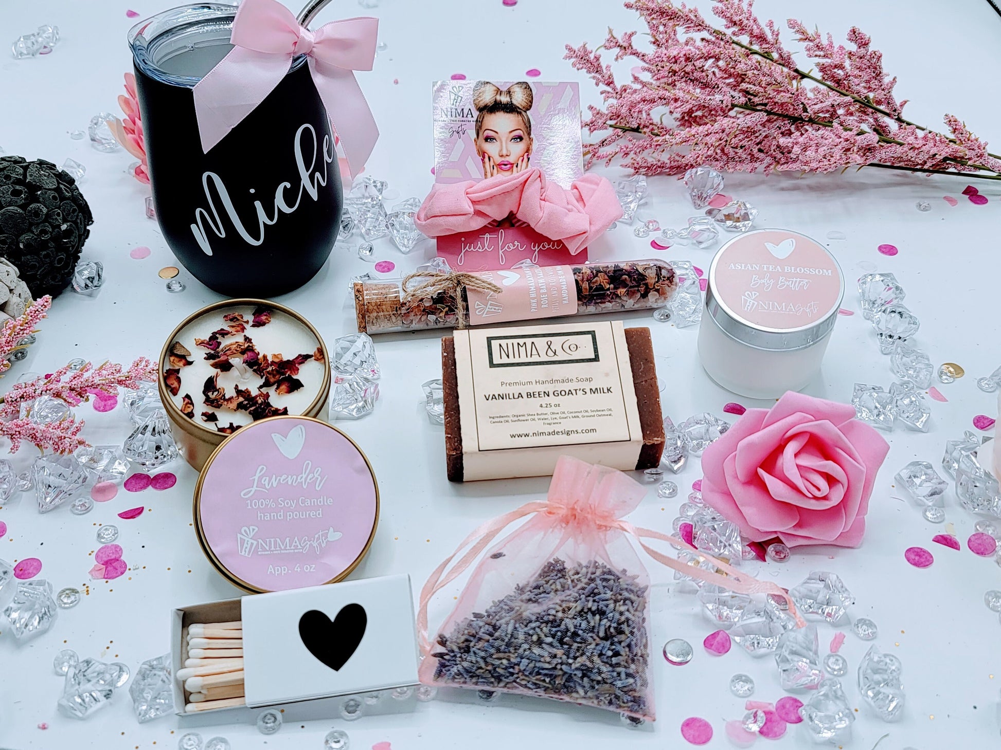Top-down view of personalized spa birthday gift box with black wine tumbler, pink scrunchie, 4oz lavender soy candle, wooden matches, 4.25oz handmade soap, lavender sachet, pink foam rose, and 4oz body lotion arranged in custom design box.