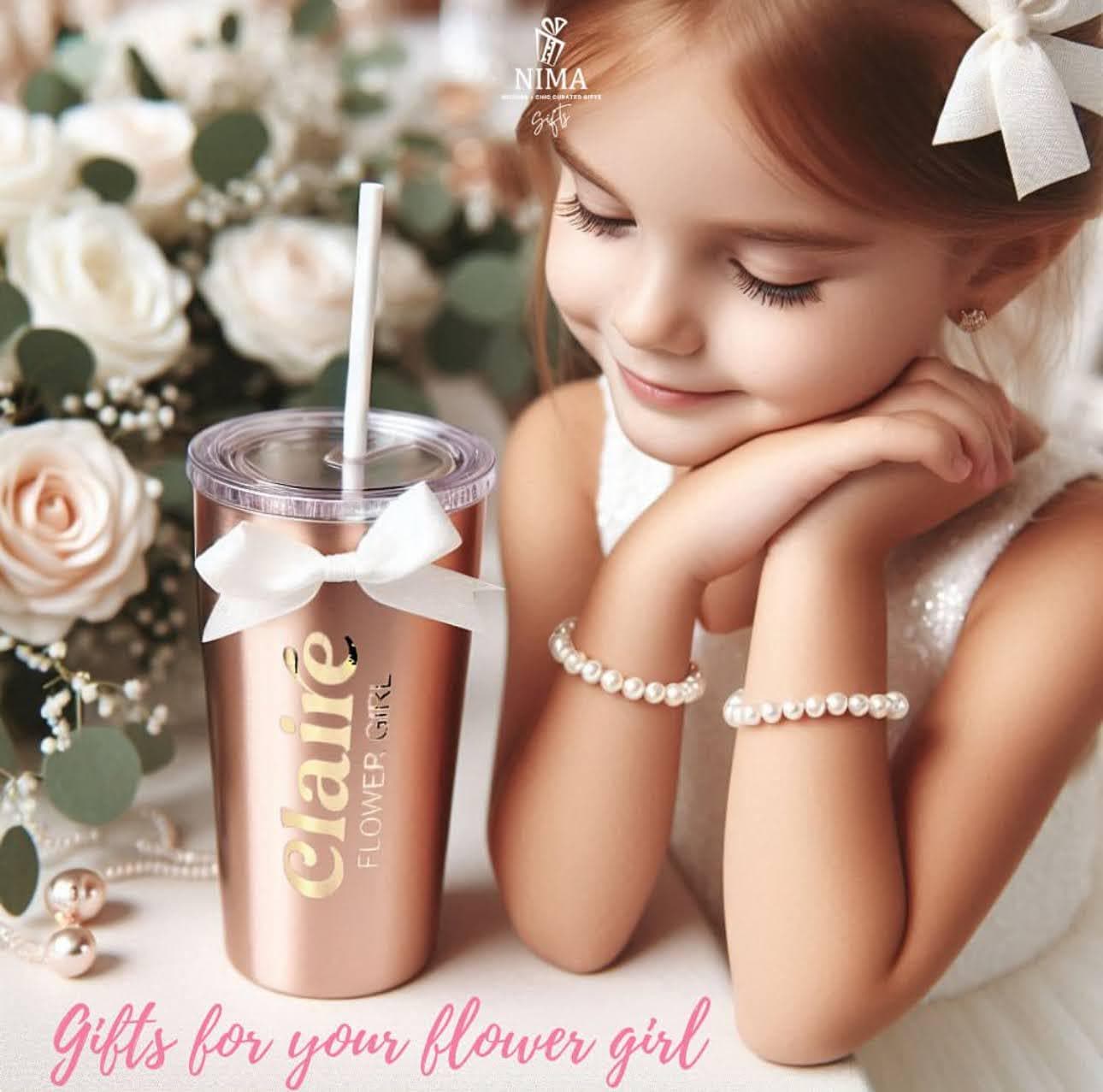 A photo of a flower girl looking at her gift of a water or juice stainless steel metal tumbler in rose gold from NIMA Gifts.