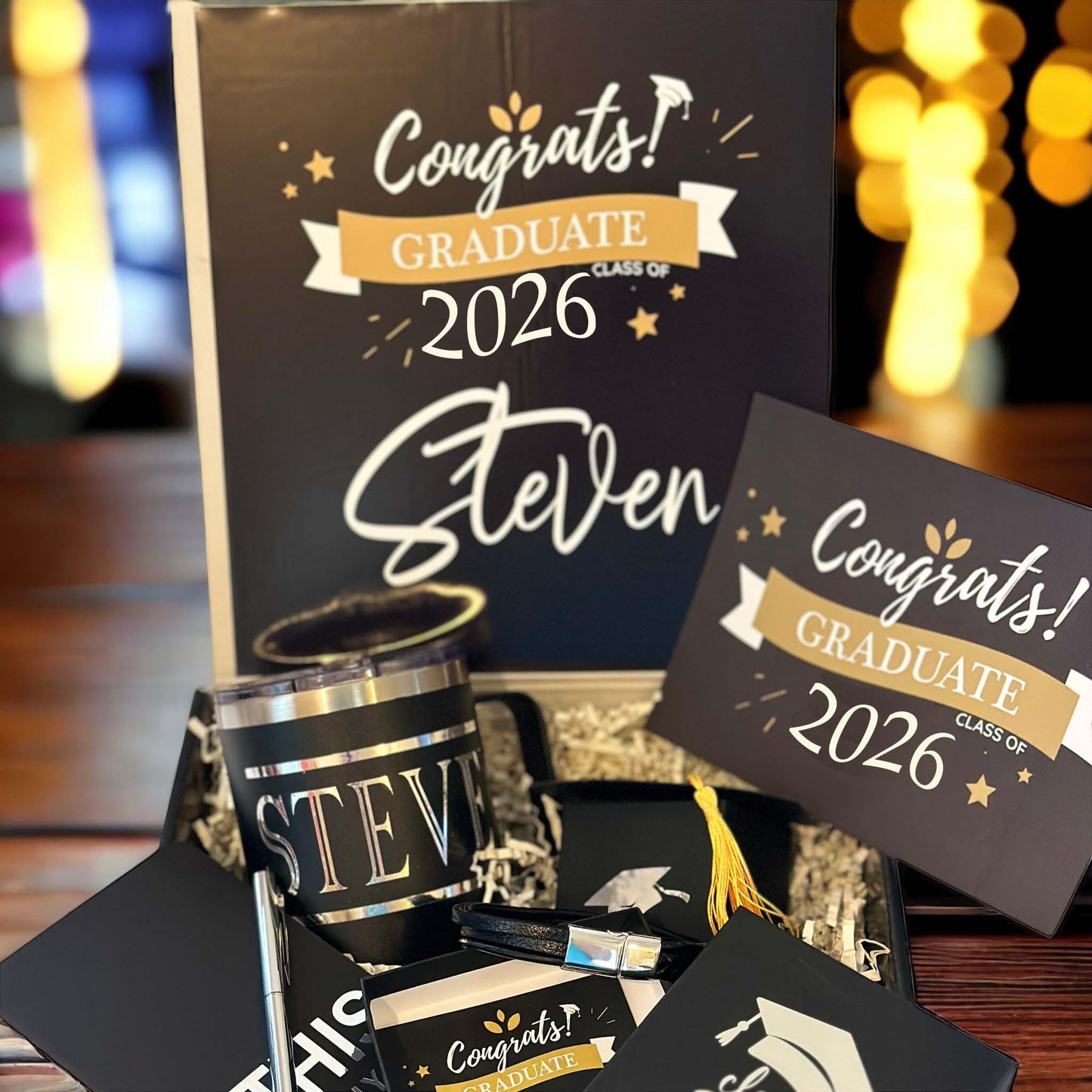 Class of 2026 graduation gift box for him featuring a personalized insulated mug, braided bracelet, inspirational notebook, sleek pen, chocolate, and custom card. Perfect graduation gift for high school or college grad. Thoughtful and ready-to-gift keepsake box in black with gold ribbon. Unique graduation gift idea for son, boyfriend, brother, nephew or best friend. Celebrate his achievement with a meaningful, personalized grad box he’ll always remember.