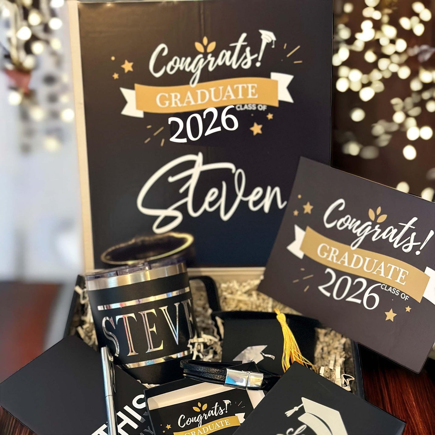 Class of 2026 graduation gift box for him featuring a personalized insulated mug, braided bracelet, inspirational notebook, sleek pen, chocolate, and custom card. Perfect graduation gift for high school or college grad. Thoughtful and ready-to-gift keepsake box in black with gold ribbon. Unique graduation gift idea for son, boyfriend, brother, nephew or best friend. Celebrate his achievement with a meaningful, personalized grad box he’ll always remember.