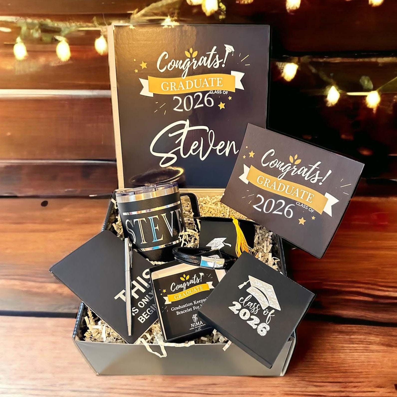 Class of 2026 graduation gift box for him featuring a personalized insulated mug, braided bracelet, inspirational notebook, sleek pen, chocolate, and custom card. Perfect graduation gift for high school or college grad. Thoughtful and ready-to-gift keepsake box in black with gold ribbon. Unique graduation gift idea for son, boyfriend, brother, nephew or best friend. Celebrate his achievement with a meaningful, personalized grad box he’ll always remember.