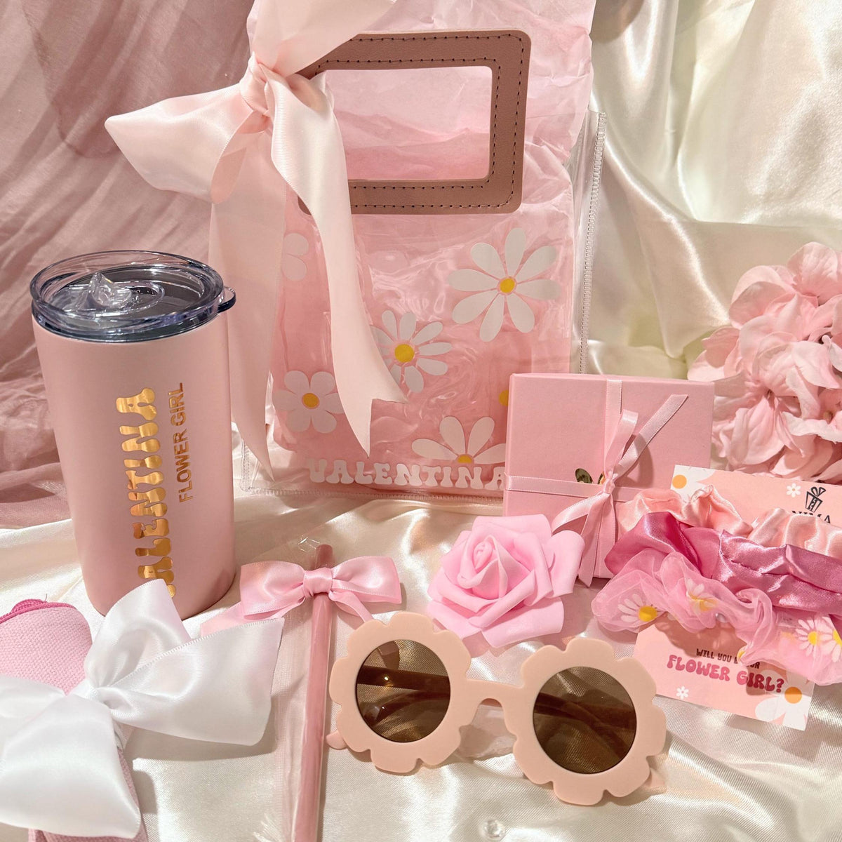 Flower Girl Proposal Gift Bag with PU leather handles, filled with personalized keepsakes like tumbler, scrunchie, sunglasses, and greeting card. A playful alternative to the flower girl proposal box, this personalized flower girl gift makes the perfect junior bridesmaid proposal gift, bridal party wedding gift, or kids wedding gift keepsake.