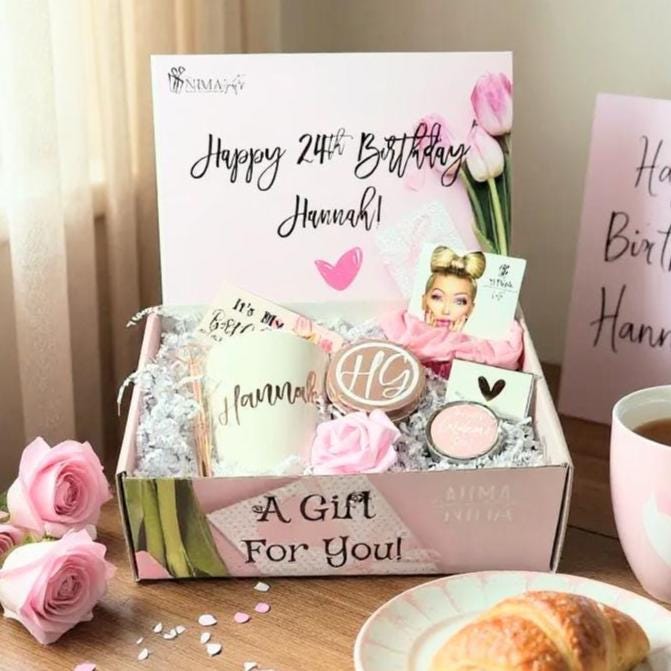 shows a pink box with tulips on it, words "A Gift for you" on the outside and personalized on the inside with a personalization on the inside. A personalized coffee mug, a rose gold candy box with initials, a small lavender ethereal candle, matches, a pink hair scrunchie and a pink rose.