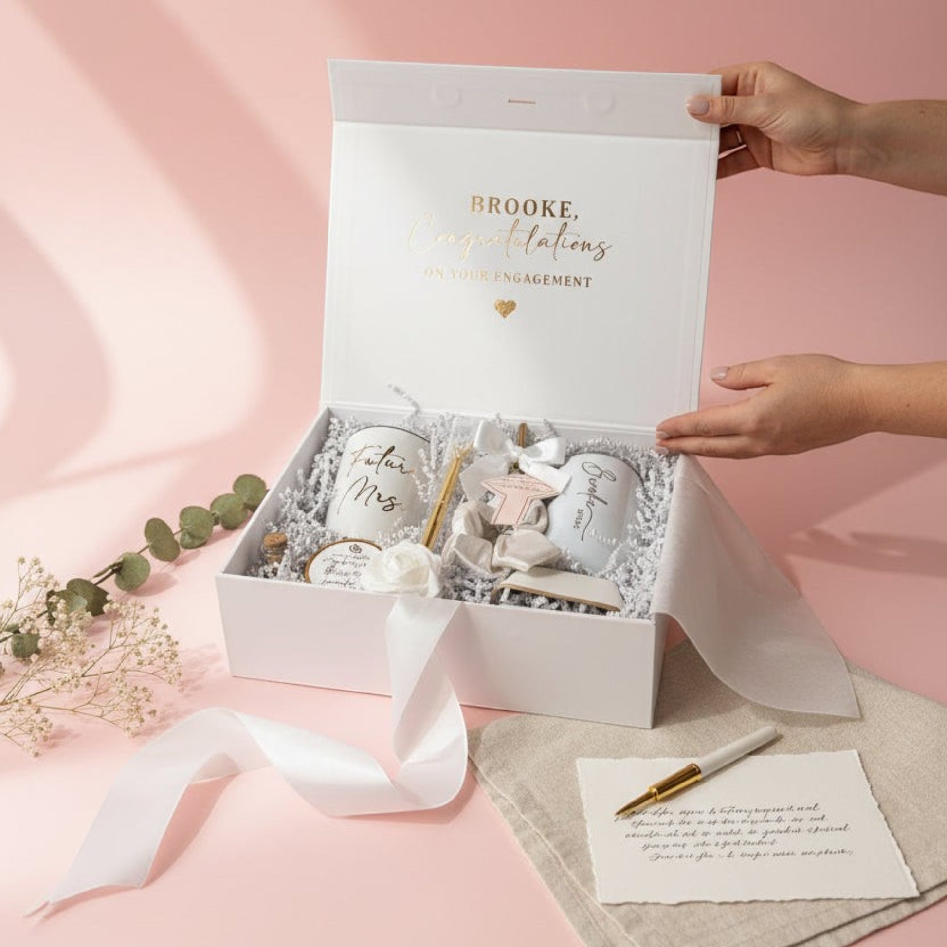 Gift box with decorative items on a pink background