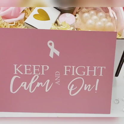 A cancer care gift box for women containing various items such as a white ceramic tea cup, bath crystals, soy candle, and lip balm, personalized with a name and a fighting message.