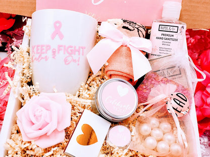 A cancer care gift box for women containing various items such as a white ceramic tea cup, bath crystals, soy candle, and lip balm, personalized with a name and a fighting message.