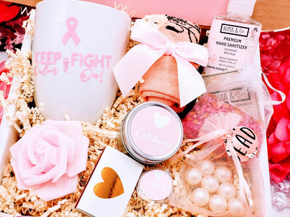 A cancer care gift box for women containing various items such as a white ceramic tea cup, bath crystals, soy candle, and lip balm, personalized with a name and a fighting message.